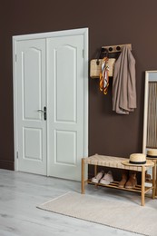 Photo of Stylish hallway interior with coat rack and bench