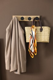 Photo of Coat rack with wicker bag and jacket on brown wall in hallway