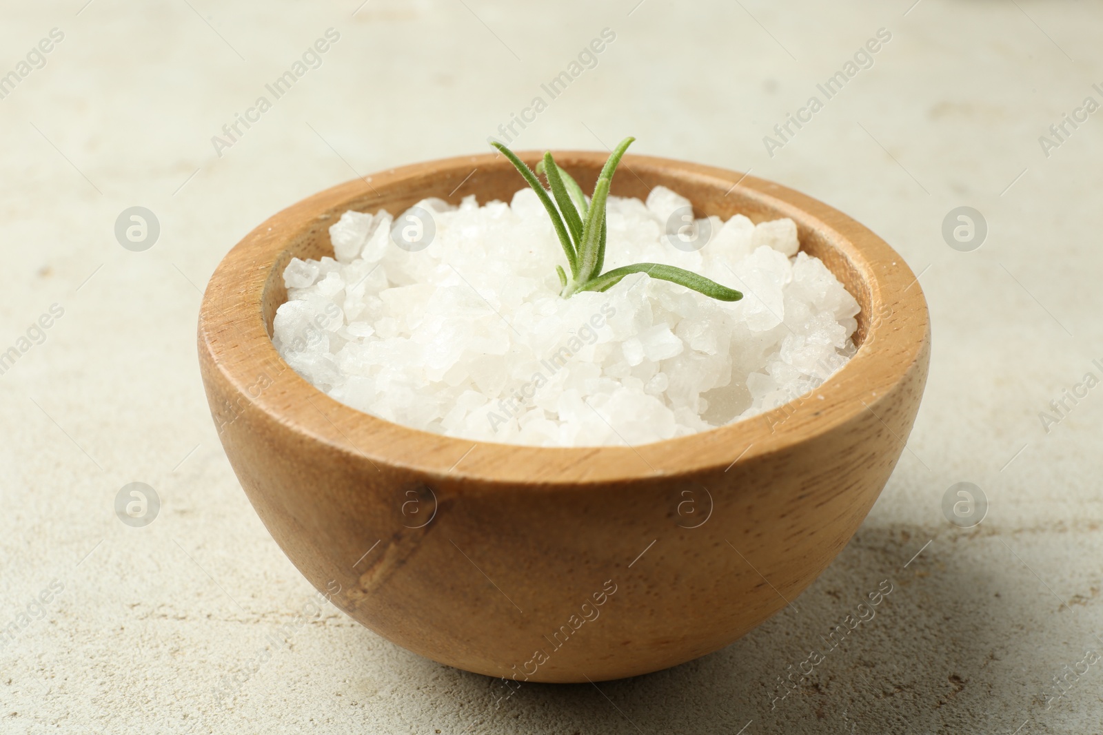 Photo of Sea salt and rosemary in bowl on grey table, closeup