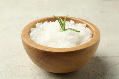 Photo of Sea salt and rosemary in bowl on grey table, closeup