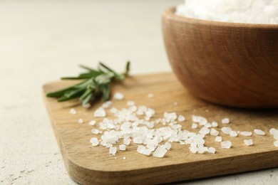 Photo of Sea salt and rosemary on grey table, closeup