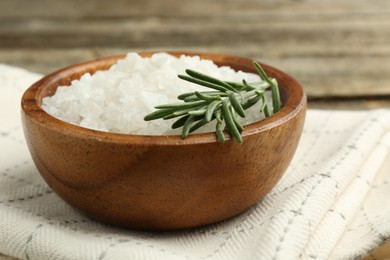 Sea salt in bowl and rosemary on table, closeup