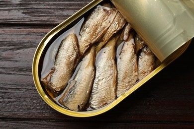 Photo of Tasty sprats in tin can on wooden table, top view