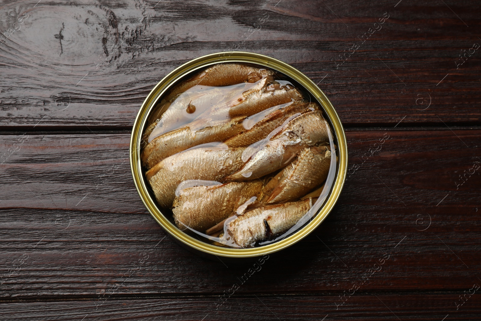 Photo of Tasty sprats in tin can on wooden table, top view