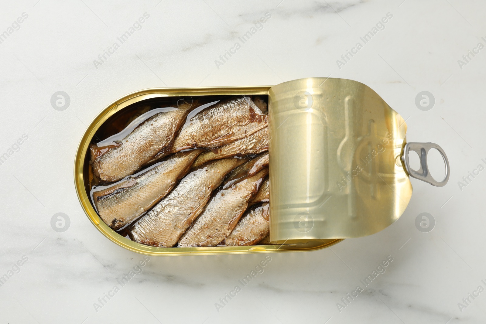 Photo of Tasty sprats in tin can on white marble table, top view