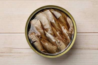 Photo of Tasty sprats in tin can on wooden table, top view