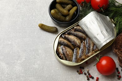 Tasty sprats in tin can served on grey textured table, flat lay. Space for text