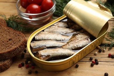 Photo of Tasty sprats in tin can served on wooden table, closeup