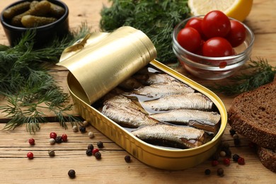 Photo of Tasty sprats in tin can served on wooden table, closeup