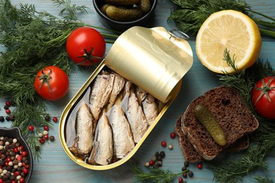 Tasty sprats in tin can served on light blue wooden table, flat lay