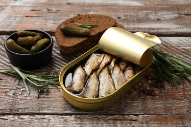 Photo of Tasty sprats in tin can served on wooden table, closeup