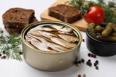 Tasty sprats in tin can served on white table, closeup