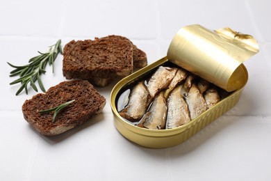 Tasty sprats in tin can served on white tiled table