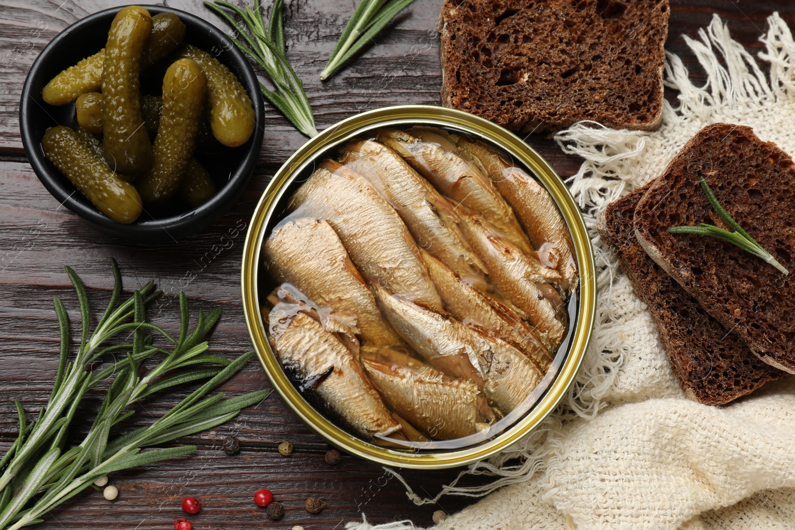 Photo of Tasty sprats in tin can served on wooden table, flat lay