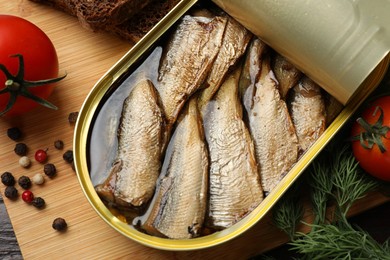 Photo of Tasty sprats in tin can served on table, flat lay