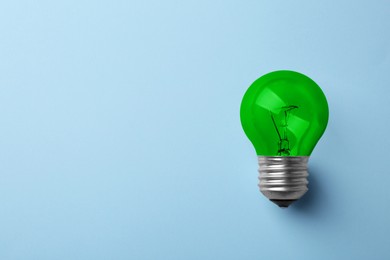 Image of Green bulb on light blue background, space for text