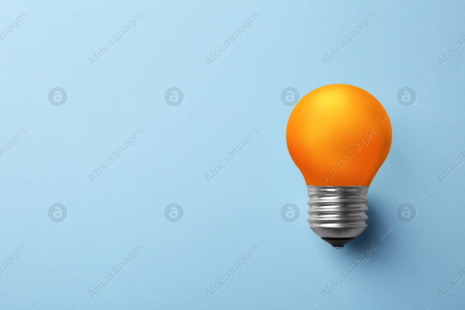 Image of Orange bulb on light blue background, space for text