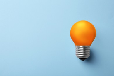 Image of Orange bulb on light blue background, space for text