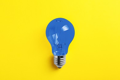 Image of One blue light bulb on yellow background