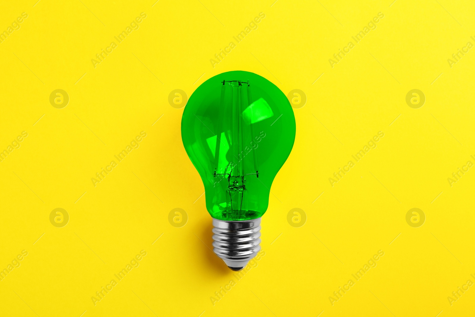 Image of One green light bulb on yellow background