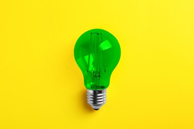 Image of One green light bulb on yellow background