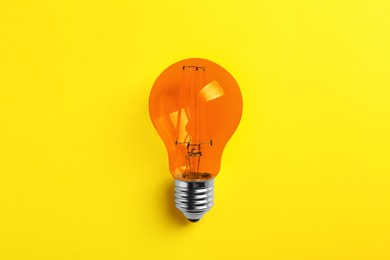 Image of One orange light bulb on yellow background