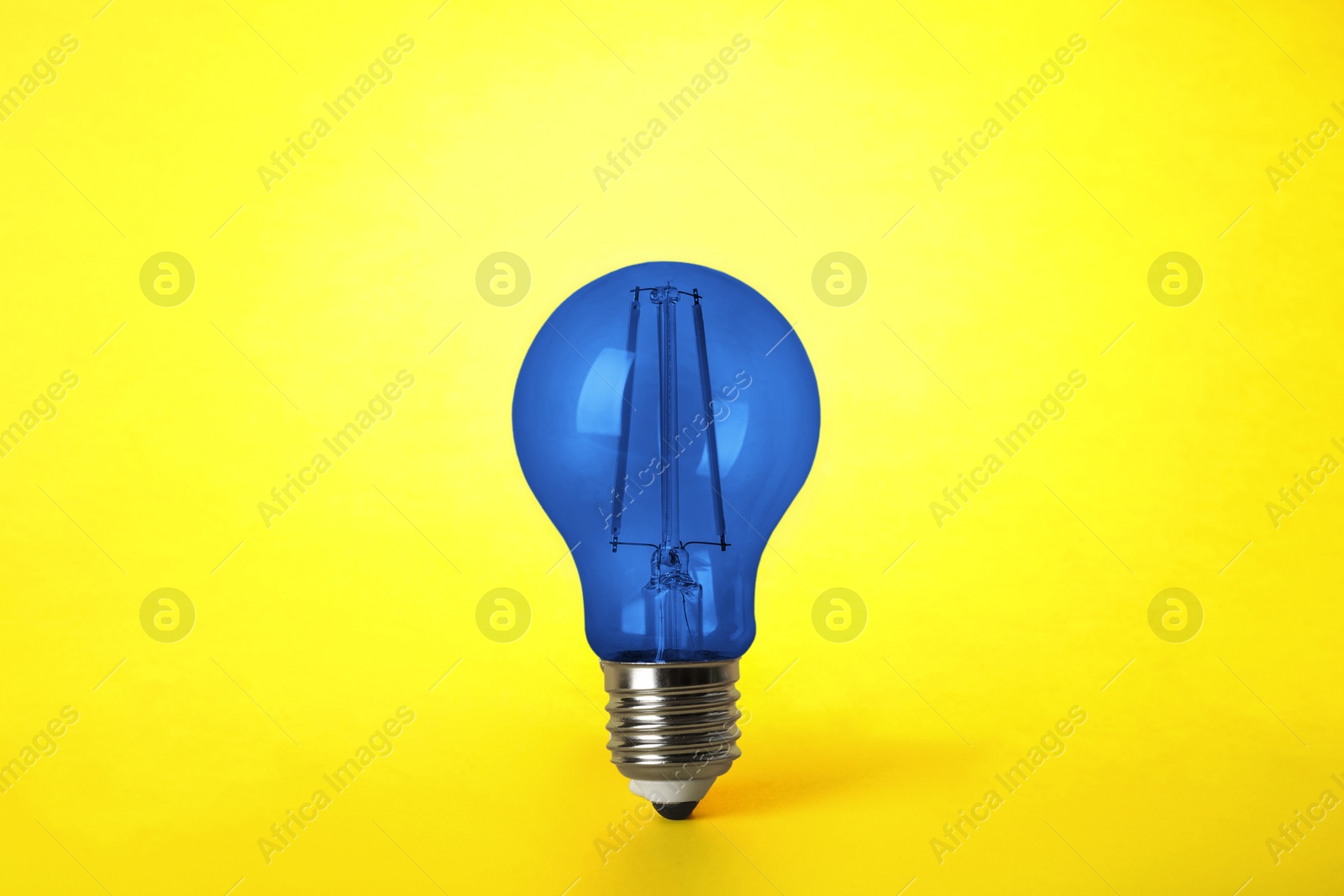 Image of One blue light bulb on yellow background