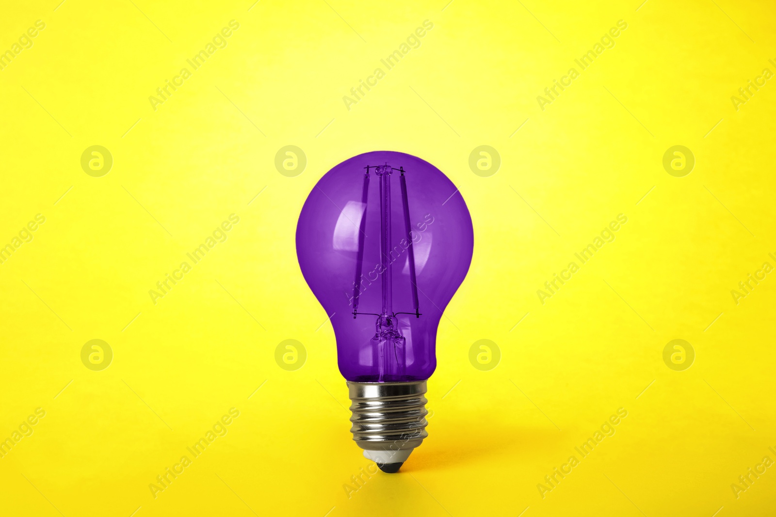 Image of One purple light bulb on yellow background