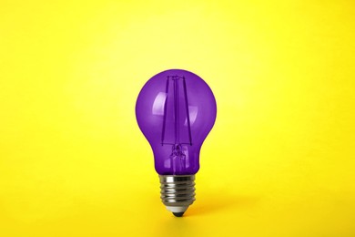 Image of One purple light bulb on yellow background