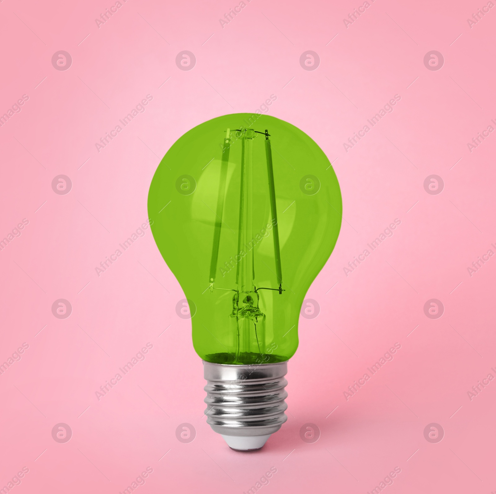 Image of One green light bulb on pink background