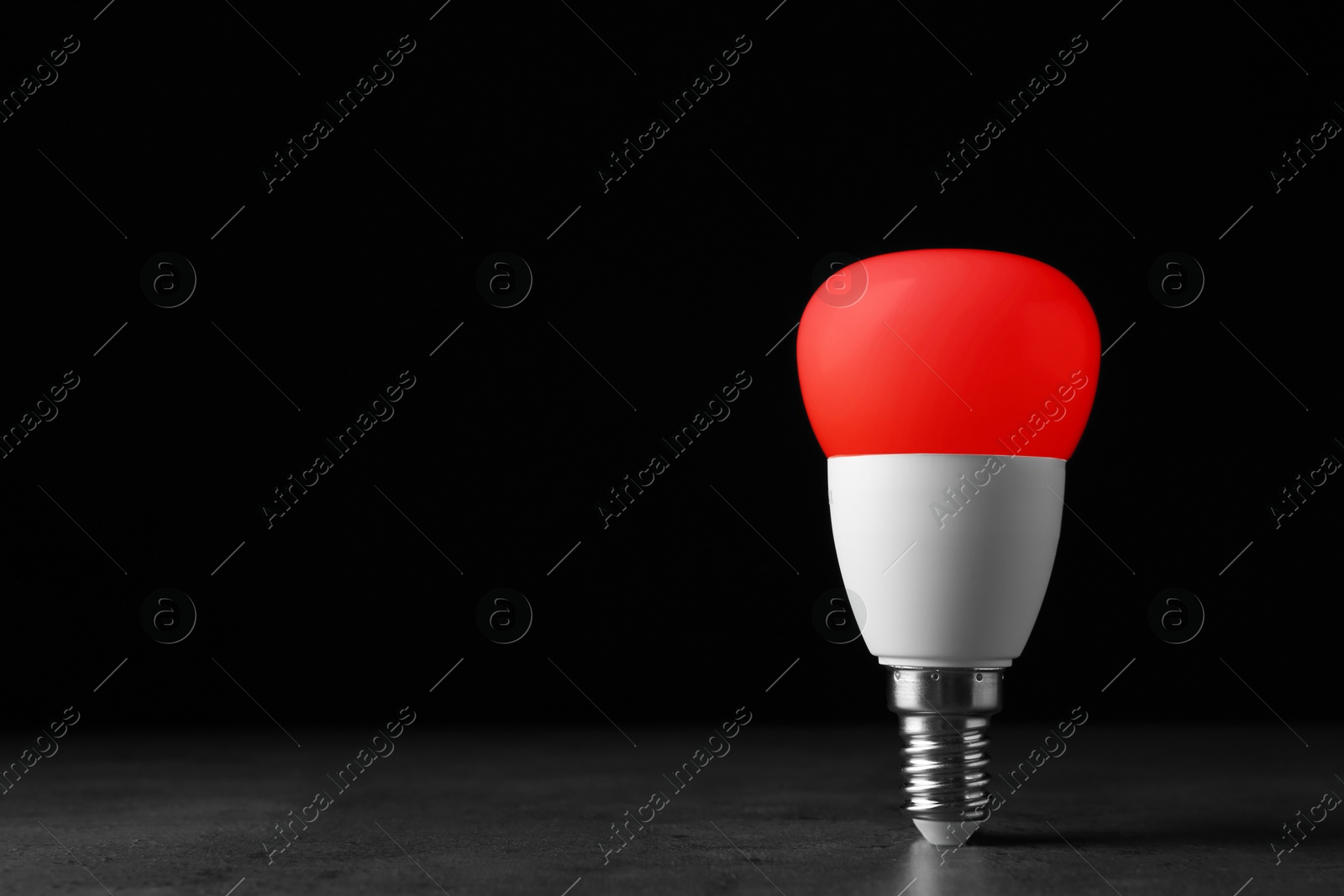 Image of Red light bulb against black background, space for text