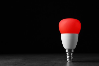 Image of Red light bulb against black background, space for text