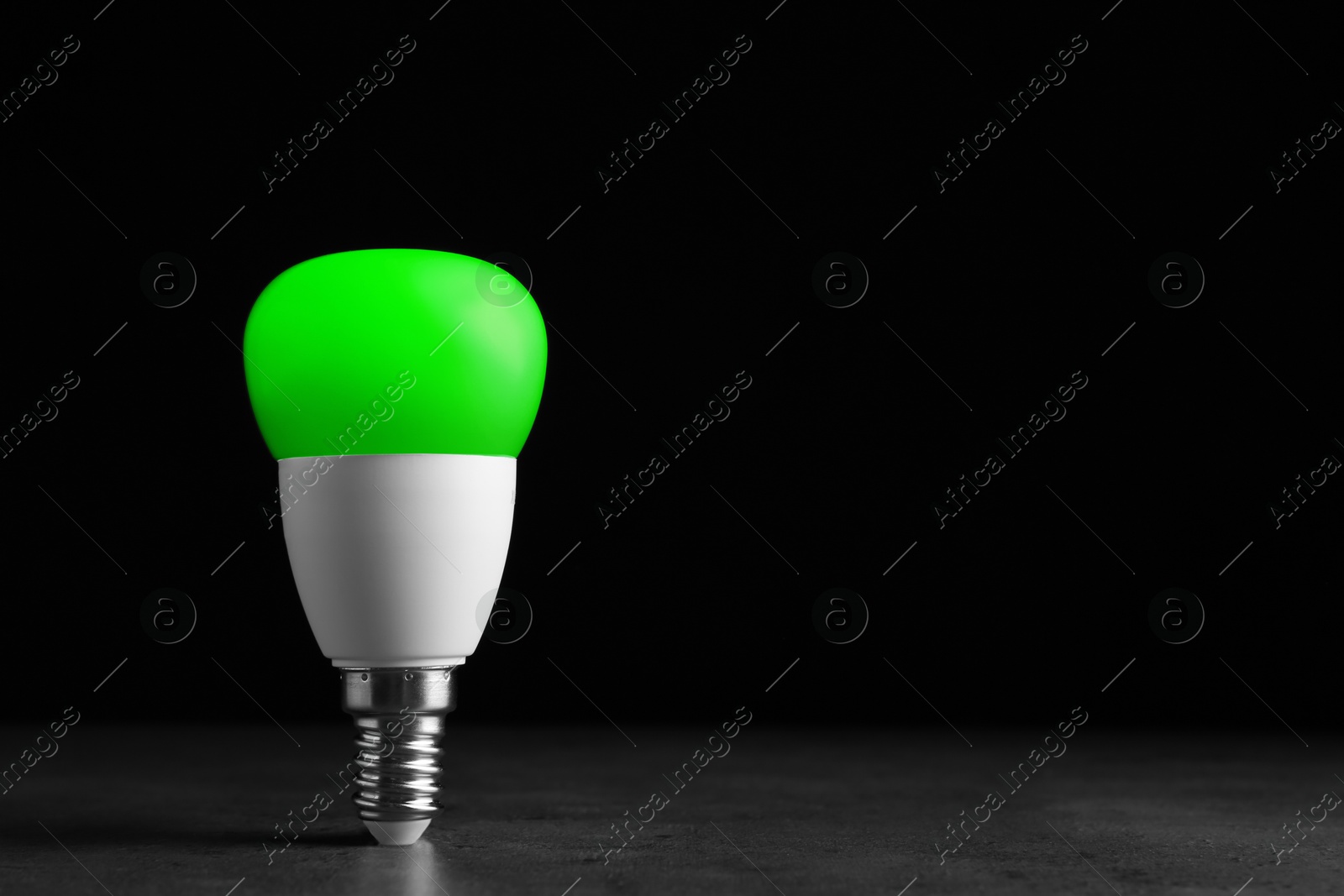 Image of Green light bulb against black background, space for text