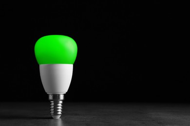 Image of Green light bulb against black background, space for text