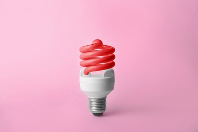 Image of Red fluorescent lamp bulb on pink background