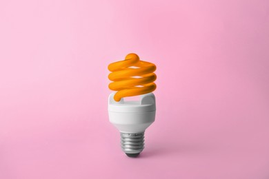 Image of Orange fluorescent lamp bulb on pink background