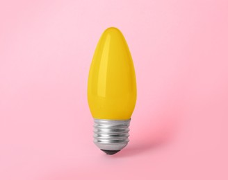 One yellow light bulb on pink background