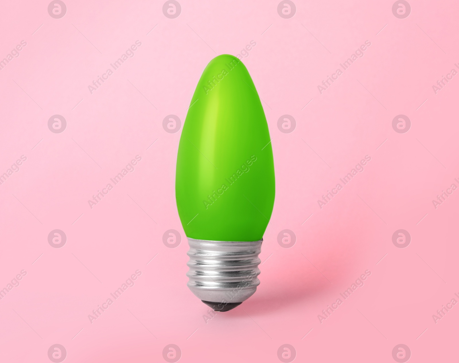 Image of One green light bulb on pink background