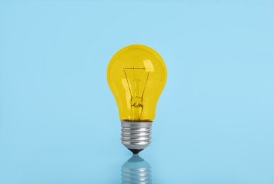 Image of One yellow bulb on light blue background