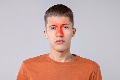 Young man suffering from sinusitis on light grey background