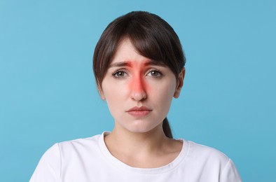 Young woman suffering from sinusitis on light blue background