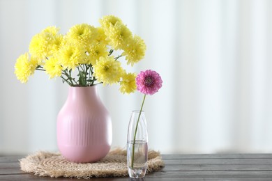 Photo of Beautiful yellow flowers in vases on wooden table at home. Space for text