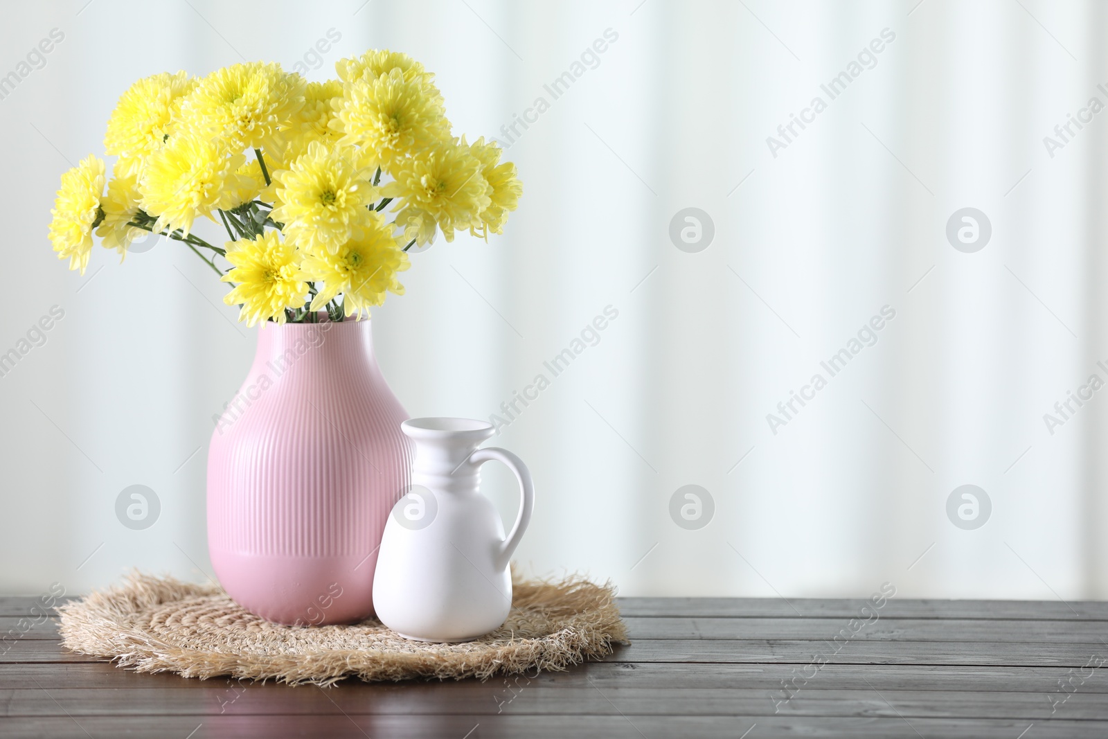 Photo of Beautiful yellow flowers in vase on wooden table at home. Space for text