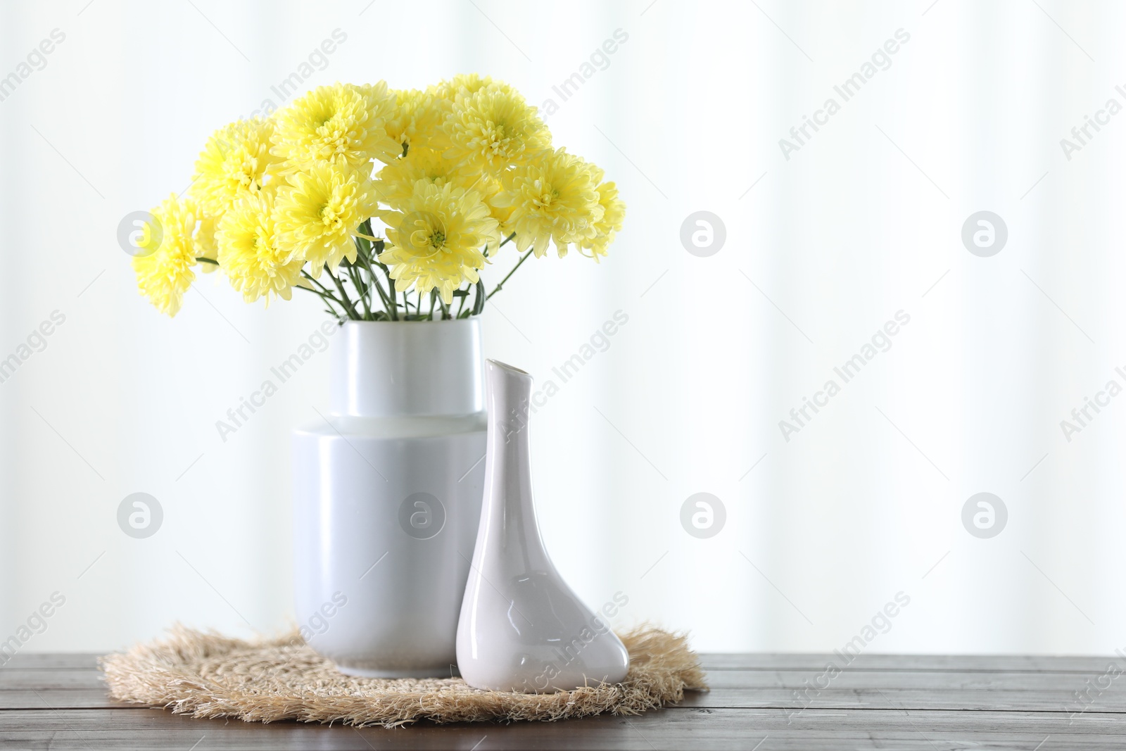 Photo of Vase with beautiful yellow flowers and empty one on wooden table indoors. Space for text