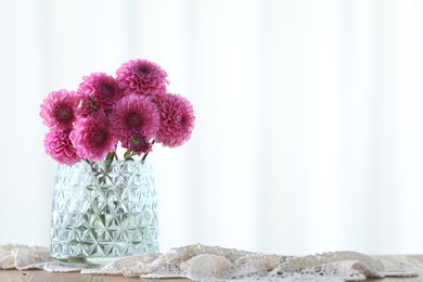 Photo of Beautiful pink flowers in vase on wooden table at home. Space for text