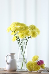 Photo of Beautiful yellow flowers in vase on wooden table at home