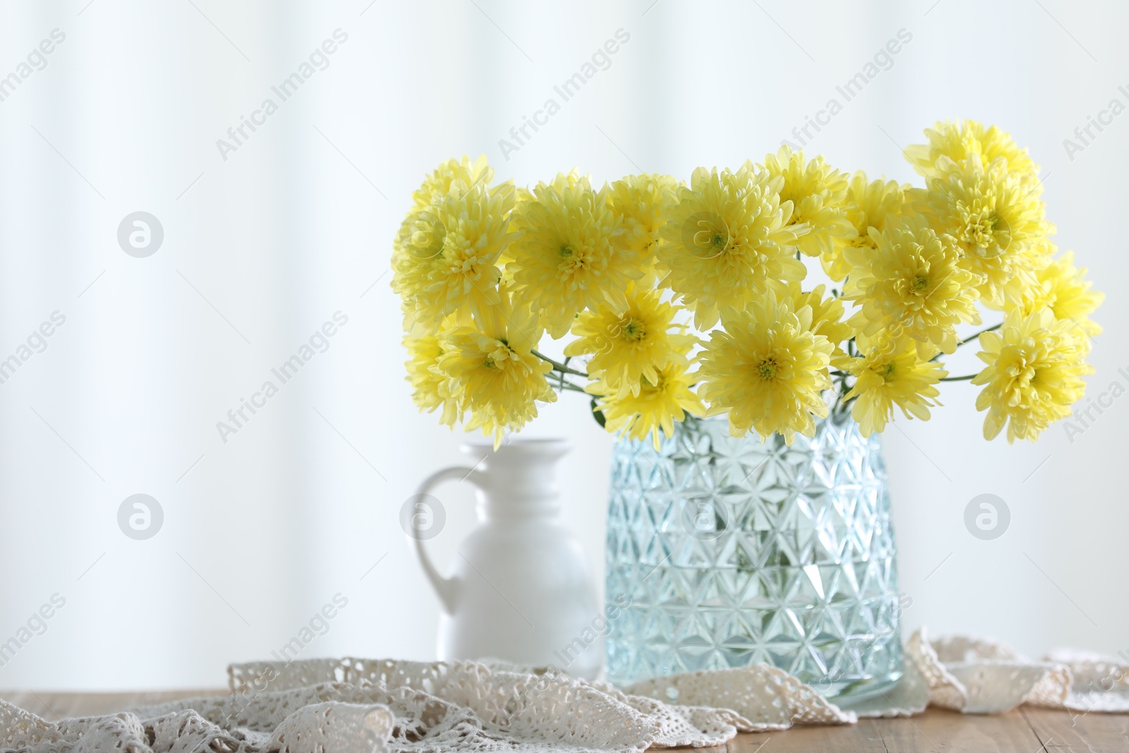 Beautiful yellow flowers in vase on wooden table at home. Space for text Photo of Beautiful yellow flowers in vase on wooden table at home. Space for text