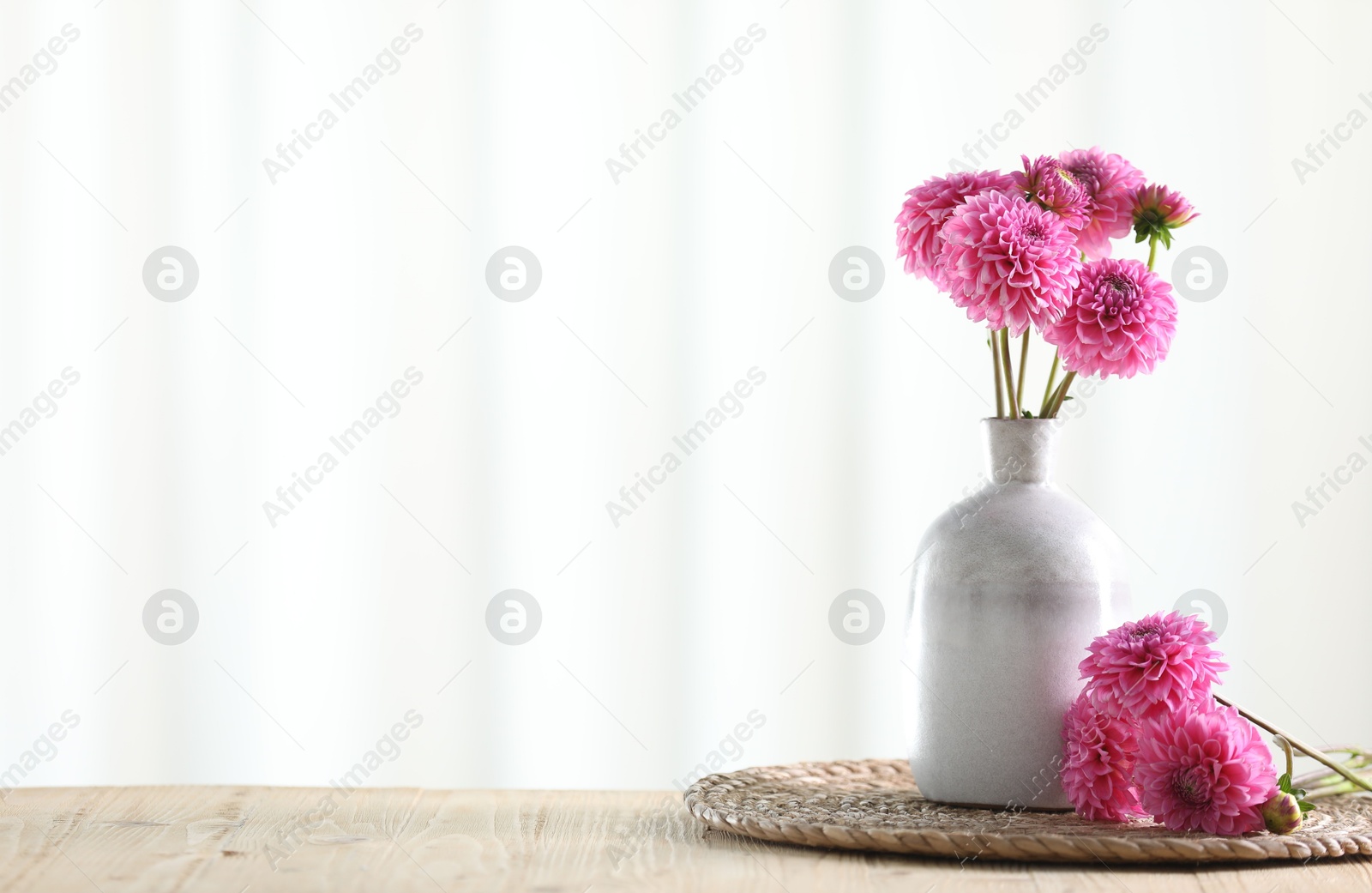 Beautiful pink flowers in vase on wooden table at home. Space for text Photo of Beautiful pink flowers in vase on wooden table at home. Space for text