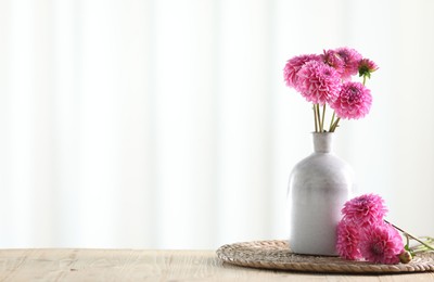 Photo of Beautiful pink flowers in vase on wooden table at home. Space for text