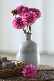 Photo of Beautiful pink flowers in vase and burning candle on table at home